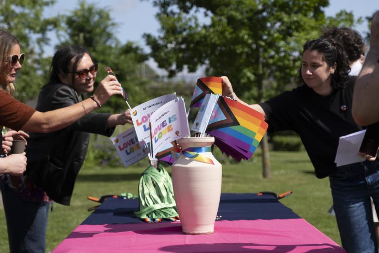 Staff and students take a small Pride flag at the Pride month flag raising event