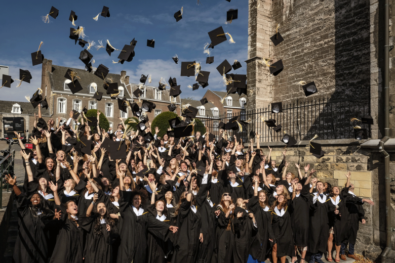 Graduates in gown throwing their caps in the air
