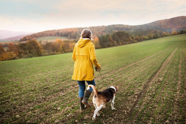 Woman walking her dog in a hilly landscape