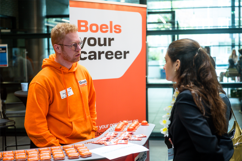 Man in orange sweater talking to a woman at a fair