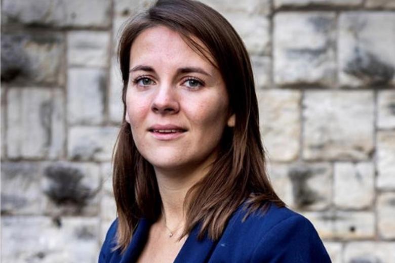 Marieke Hopman stands in front of a stone wall.