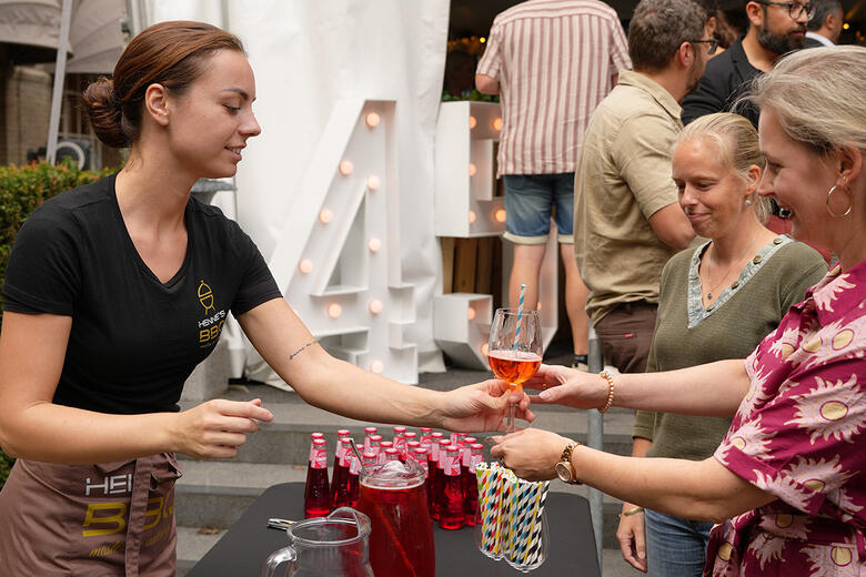 Een medewerker die een drankje overhandigd krijgt tijdens de staf barbecue.